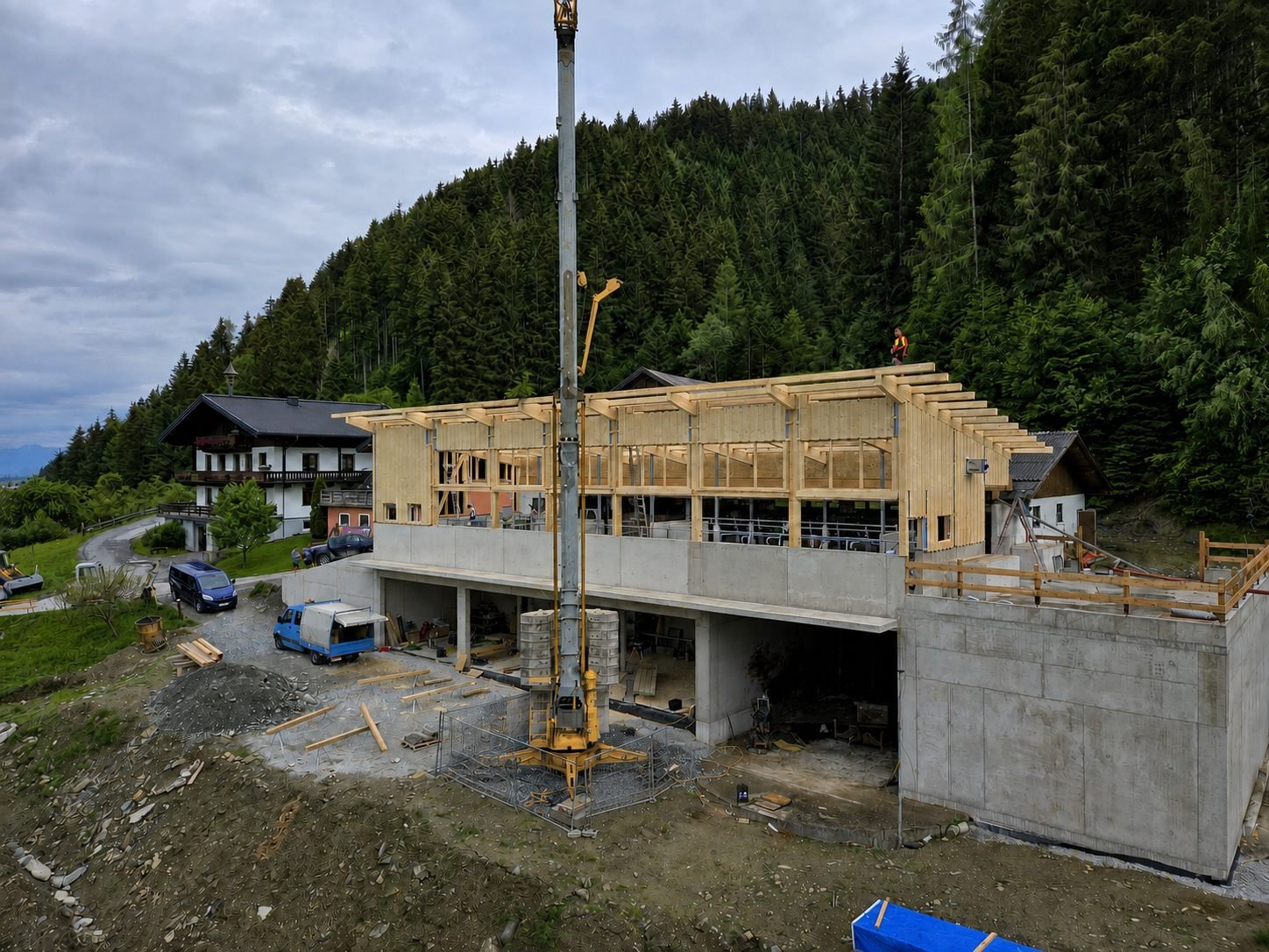 Holzrahmenbau im Rohbau mit Kran, eingebettet in die Bergkulisse