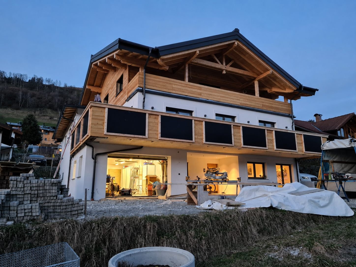 Fertiggestelltes Chalet in der Abenddämmerung mit beleuchteter Werkstatt